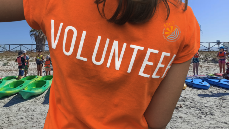 Volontario ASD di spalla con t-shirt arancio del club che scatta foto ai bimbi che stanno per uscire in kayak